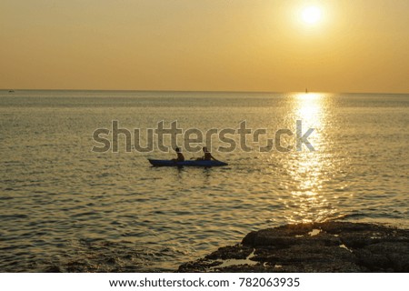 amazing tropical orange sunset over water, with rock silhouettes and a boat on Phuket Island, Thailand