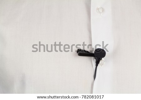 Black lavalier microphone on white man's shirt