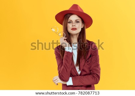 attractive woman in red in a hat with glasses on a yellow background, studio, style
