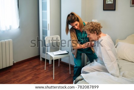 Female caregiver helping elderly female patient to get out of bed Royalty-Free Stock Photo #782087899