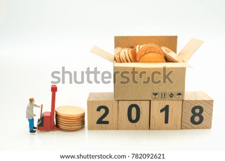 Miniature people: Worker and stack of coins with wood number 2018 using as background business, new year concept.