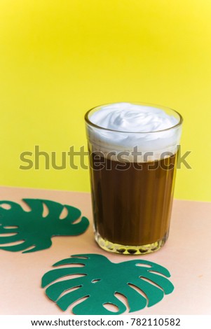 iced coffee  and green paper leaves monstera bright yellow orange pastel background