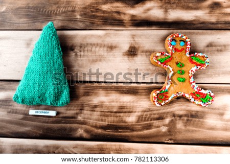 Ginger biscuit in the form of a man and an artificial green tree on a natural dark wooden background.