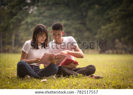 couple of high school students sit down and read a book in park, education concept