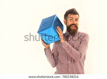 Surprise and holiday gift concept. Guy in plaid shirt holds present box. Man with beard and cheerful face isolated on white background. Macho with wrapped blue gift on shoulder