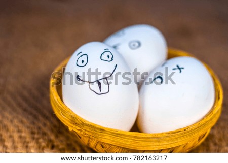 Funny faces drawn on the eggs which are in a traditional basket.