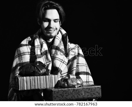 handsome bearded smiling man in checkered plaid holding colorful presents or gifts on black studio background