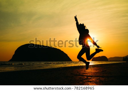 woman traveler jumping on the beach when sunrise on vacation.silhouette concept.