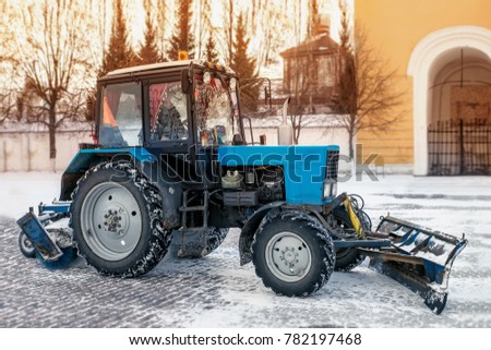 Blue bulldozer cleans the streets after a heavy natural snowfall. Getting ready for Christmas. Sunny frosty day. Close-up.