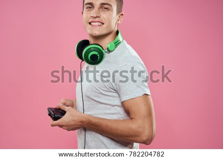 man with headphones playing joystick on a pink background                               