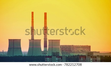 Nuclear power plant in the background of the city. Sunset. Non-operating power plant.