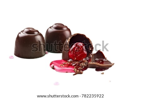 Three chocolate covered cherries isolated over white background with clipping path included. Shallow depth of field with selective focus on bitten portion of truffle with exposed cherry.