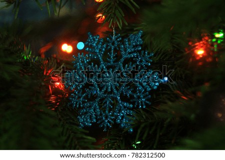 Close up photo of decorative blue snowflake hanging on the Christmas tree