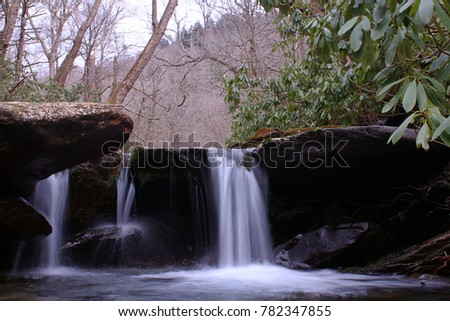 Slow Shutter Speed Photography of a Small River Waterfall with Moss Covered Rocks.