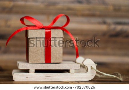 Gift box with a red ribbon on wooden sledges. Christmas holidays. Wooden background.