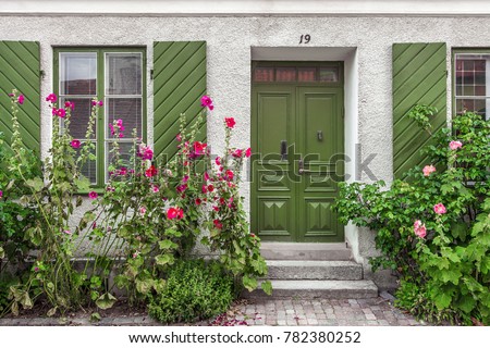 Beautiful views of Visby, main city on Gotland, island in Baltic Sea in Sweden.Best-preserved historical medieval city in Scandinavia. Front view of white stone house with green wooden door, shutters. Royalty-Free Stock Photo #782380252
