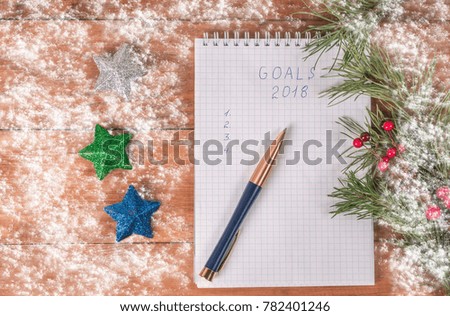 Christmas decorations, spruce branches and a notebook with tasks and a pen. wooden background with snow