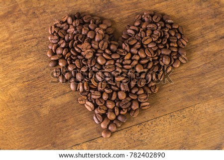 Coffee beans in the shape of heart on wooden background