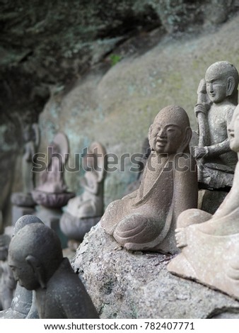 Very old Buddhist arhat stone statue found in a small cave alcove while hiking on Mt. Nokogiri in Japan. Has a wonderful joyful expression on his face while seated in a yoga meditation position.