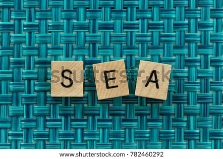 Sea spelled with small block tile letters with a bright blue background