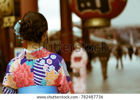 Rear angle shot of a traditional Japanese woman in a Kimono looking towards the Hanzomon Gate of Senso-ji temple. Senso-ji is a colorful and popular Buddhist temple located in Asakusa, Tokyo, Japan. 
