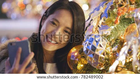 Woman taking selfie on mobile phone over christmas tree decoration 