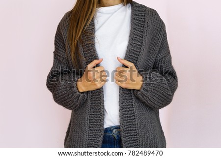 woman in fashionable gray knitted cardigan stands against the background of a pink wall Royalty-Free Stock Photo #782489470