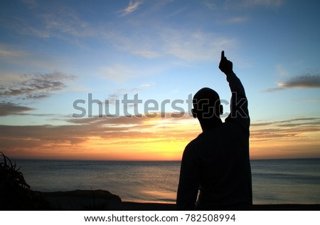 sunset with man looking up and pointing to the sky and praying to god with sky background stock photo Royalty-Free Stock Photo #782508994