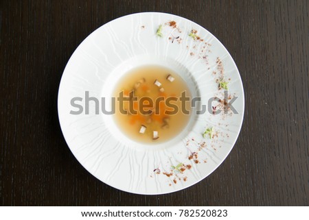 vegtable clear soup in a white bowl