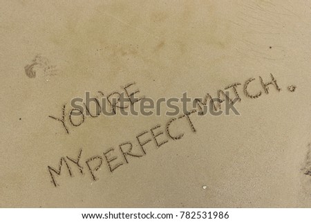 Handwriting  words "YOU'RE MY PERFECT MATCH." on sand of beach.