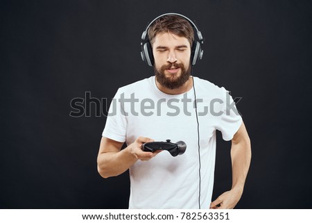 man in headphones with joystick on black background                               