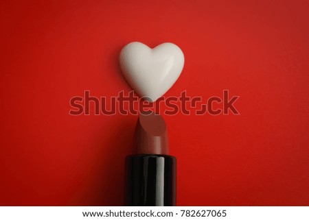 Valentine's hearts floating over lipstick on red background with copy space. Symbol of love. Happy Valentines Day background concept.