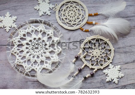 Dreamcatcher with feathers on a wooden background. Ethnic design, boho style, tribal symbol.White Christmas and New Year snowflake on a wooden vintage old background