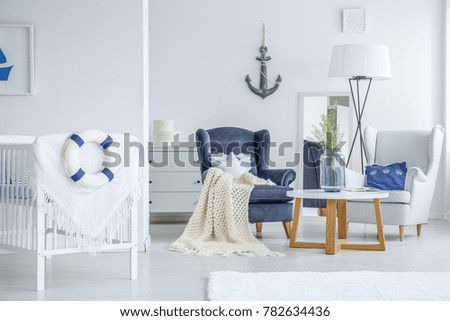 Vase with white flowers standing on a small table in bright bedroom for a toddler in marine style