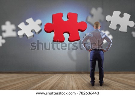 View of a Businessman in front of a wall with Puzzle pieces