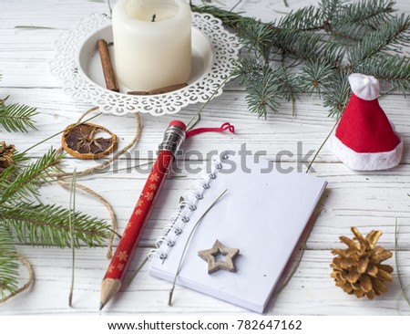 A festive winter mock up photo with a fir twigs, an opened note book, a pencil, cones, a candle and decation elements