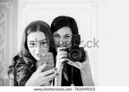 Two girls do selfie on phone and camera, best friends have fun