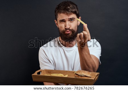 man with a potato holds a tray with fast food on a black background                              