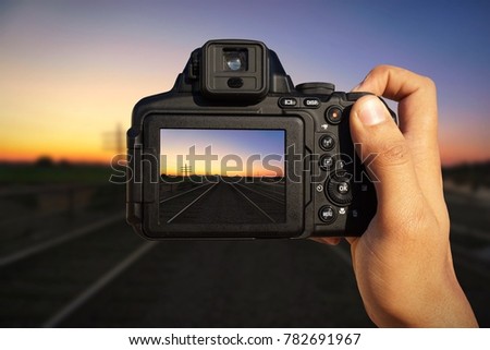 Camera in hand capturing a vibrant colorful landscape at dusk dawn on train tracks in Arizona