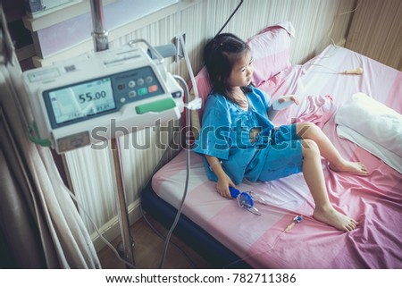 Illness asian girl admitted in hospital with infusion pump feeding IV drip. Shallow depth of field (DOF) child in focus, IV machine out of focus. Health care stories. Vintage film filter effect. Royalty-Free Stock Photo #782711386