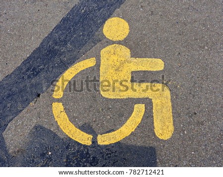 Parking sign for the disabled, pictured on the asphalt.

