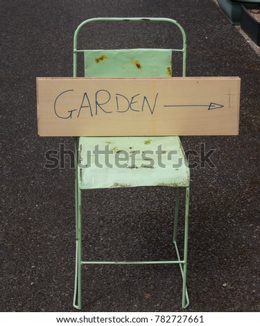 Hand Made Sign with Directions to a Garden Resting on a Rusty Vintage Chair in the Ancient Market Town of Chulmleigh in Rural Devon, England, UK