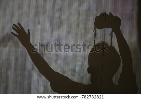 Shadow of someone holding a digital camera while waving his hand