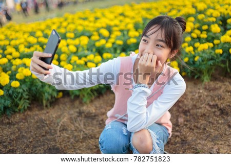 Asian girl using a smartphone photographing flowers in the flower garden