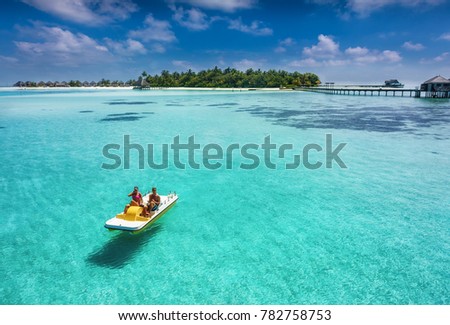 Couple on a floating pedalo boat is having fun on a tropical paradise location over turquoise waters and blue sky Royalty-Free Stock Photo #782758753