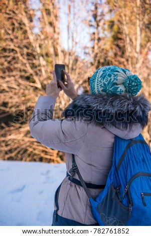 Woman 50 years old taking photo in the mountains in winter, Almaty, Kazakhstan.