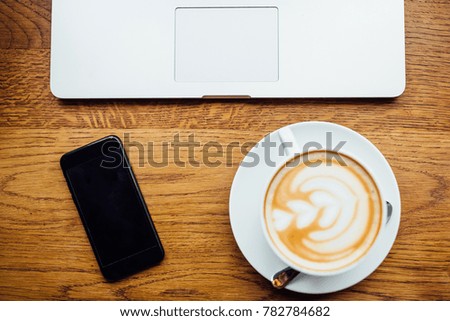 black coffee phone with a picture and a laptop lie on the same table