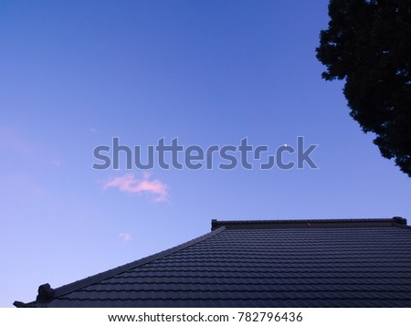 An image of a roof on traditional Japanese house under the first-quarter moon at Suzumenomiya in Utsunomiya, Tochigi, Japan in December, 2017.