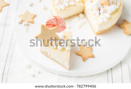 Piece of Classic cheesecake "New York" with a decor: ginger cookies, marshmallow and candy on a light wooden background. The best celebration background. Winter xmas holidays concept.