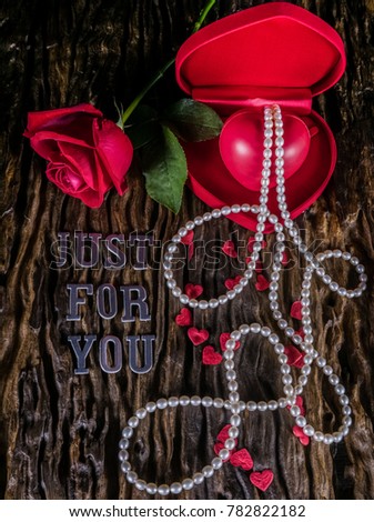 Image of arrangement for Valentine day with red rose and red heart shape model in heart shape box with pearl necklace on old wooden background and words of silver letter say just for you